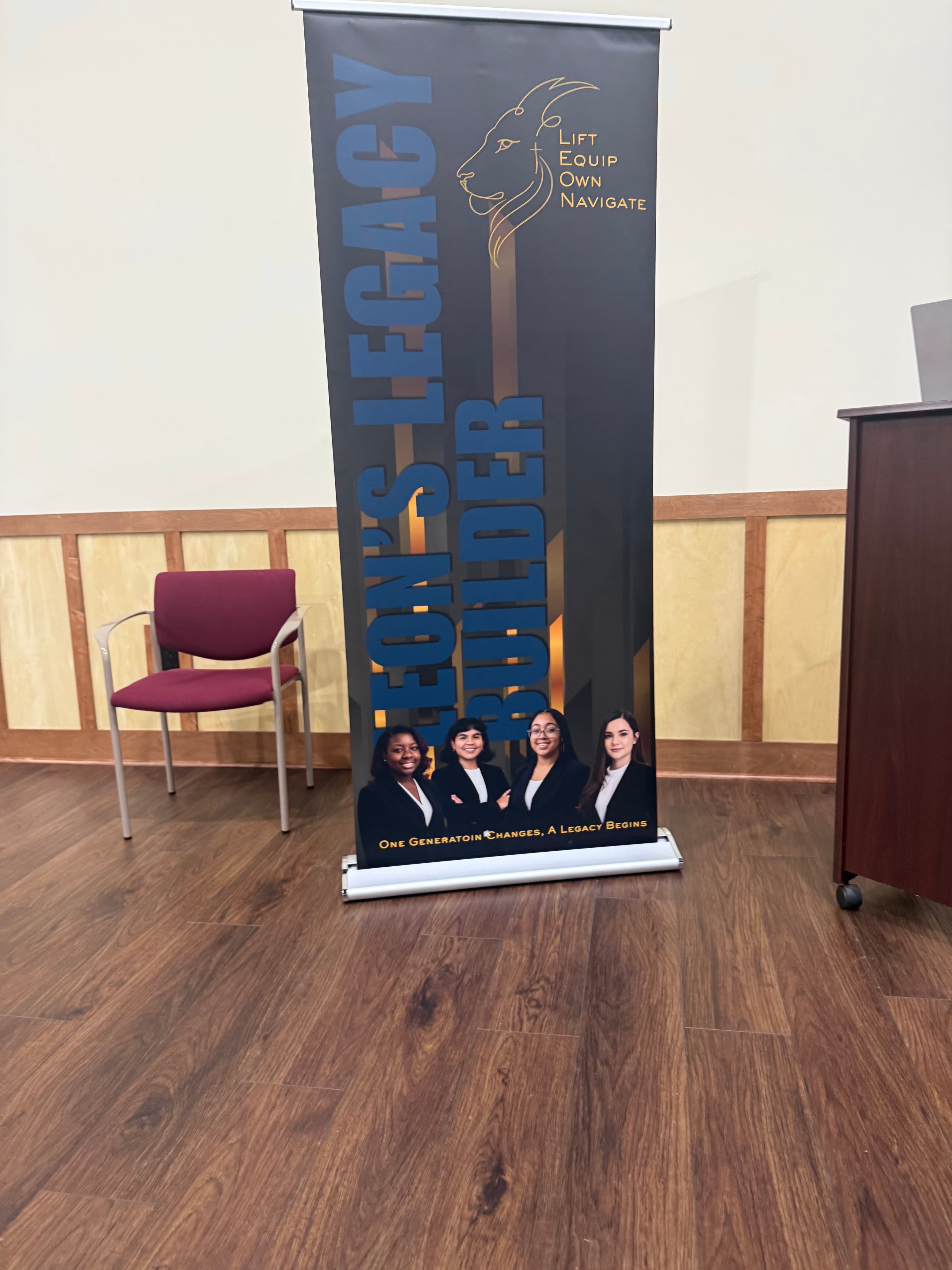 Leon's Legacy Builder banner featuring four professional women and a lion logo on wooden floor.